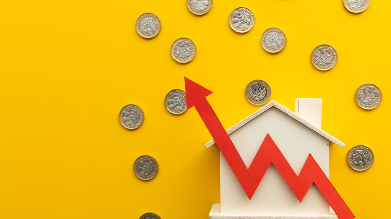 A paper house on a yellow background. There is a red arrow pointing upwards and pound coins all around the house. 