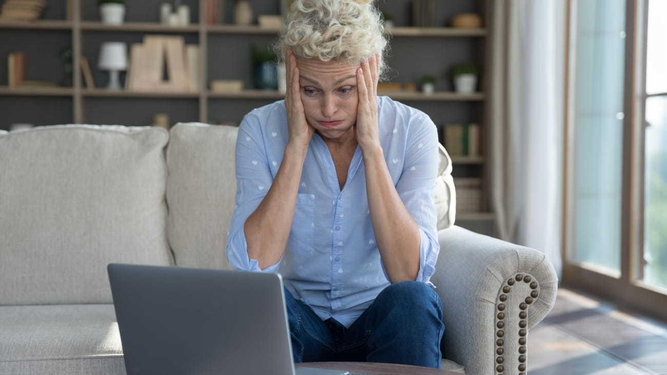 A stressed looking woman looking at her laptop screen
