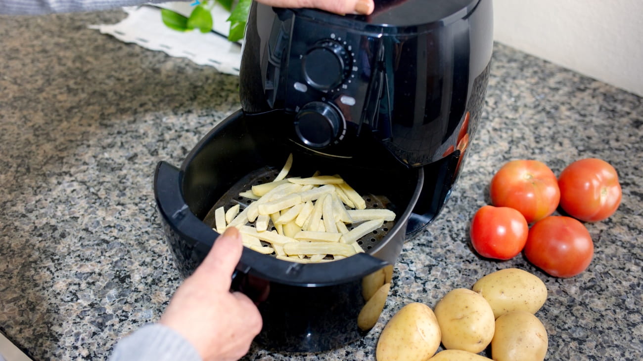 Frying sliced potatoes in the airfryer, with potatoes and tomatoes next