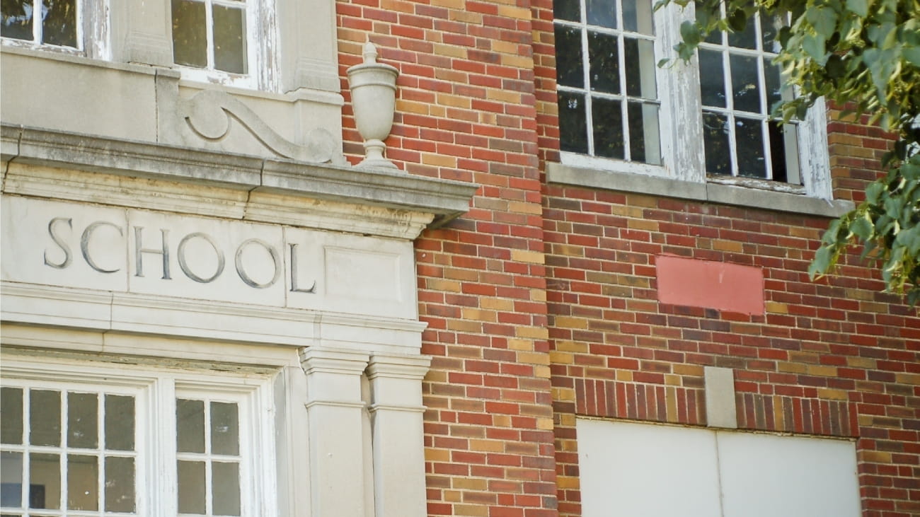A school sign in carved into stone, on red brick building.