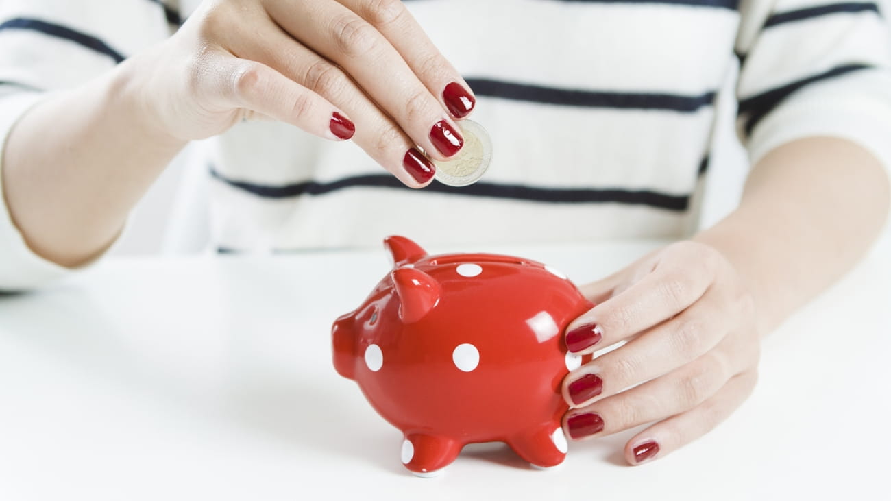 Woman saving money with red piggy bank