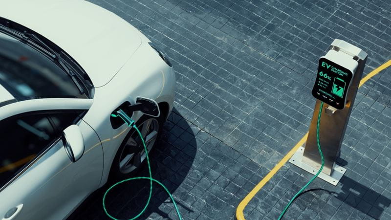 Aerial view electric car recharging battery from EV charging station at city center public car park. Future innovative rechargeable EV car using alternative clean and sustainable energy. Peruse