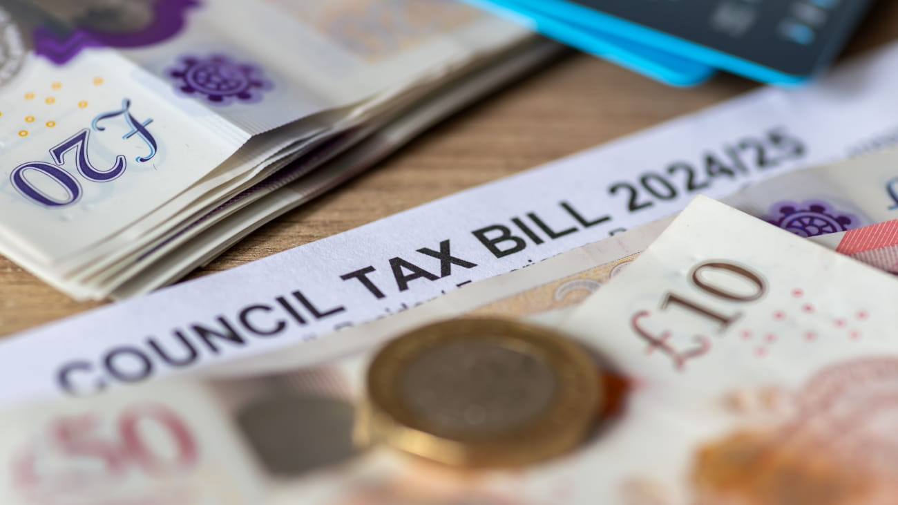 A close up of a United Kingdom local authorities Council Tax bill with bank notes, Pound coin and bank cards.