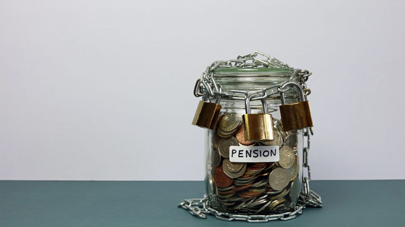 A Glass Jar Labelled Pension Full Of Money Secured With Three Padlocks.Triple Lock Pension Scheme Concept.