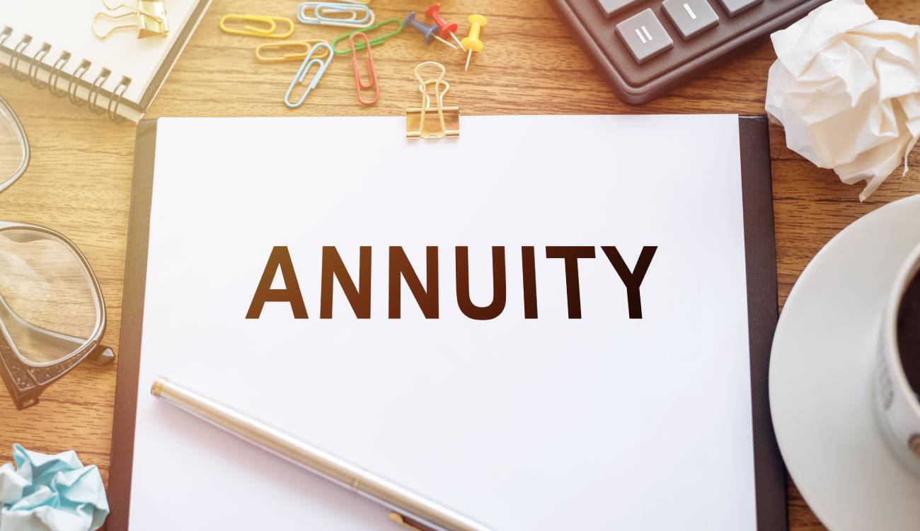 The word Annuity written on a piece of paper, set against a business background.