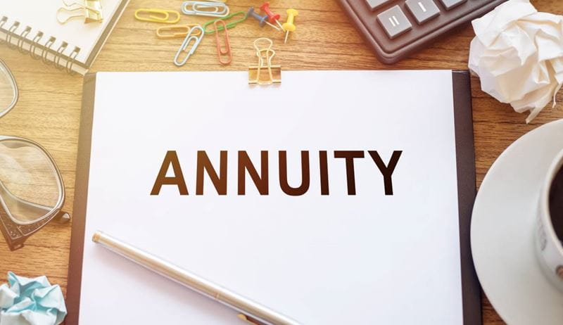The word Annuity written on a piece of paper, set against a business background.