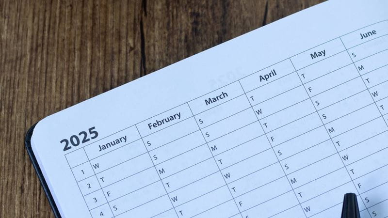 January 2025 year goal planner notebook with coffee cup on wooden desk.