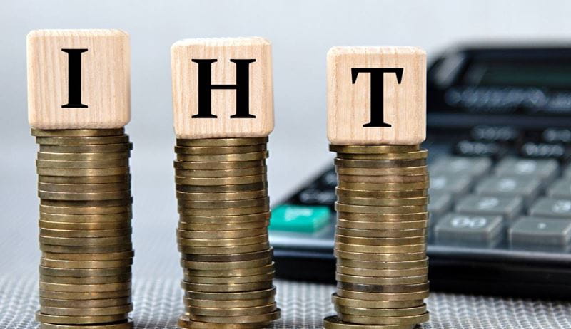 IHT (Inheritance Tax) - acronym on wooden cubes on the background of coins and calculator. Business and finance concept