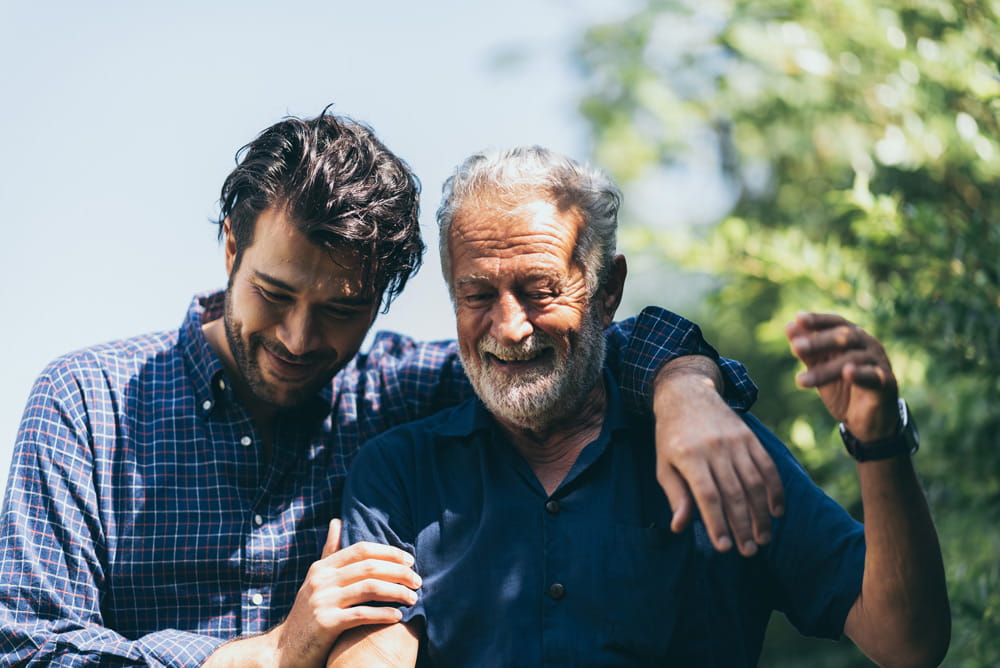 A son walking with his arm around his father's shoulders