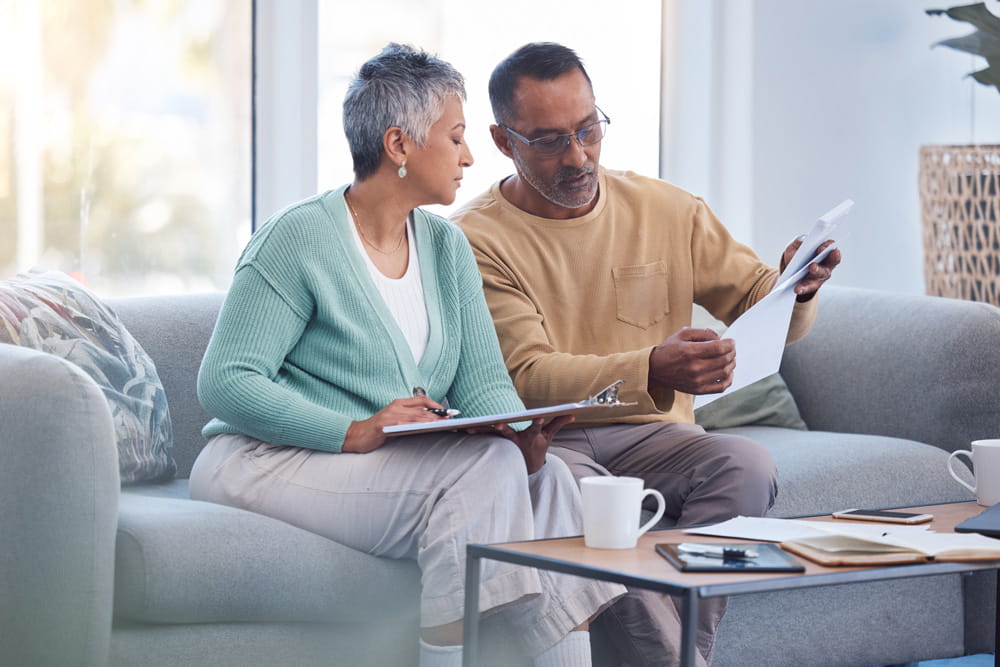 A couple looking over paperwork at home on the sofa