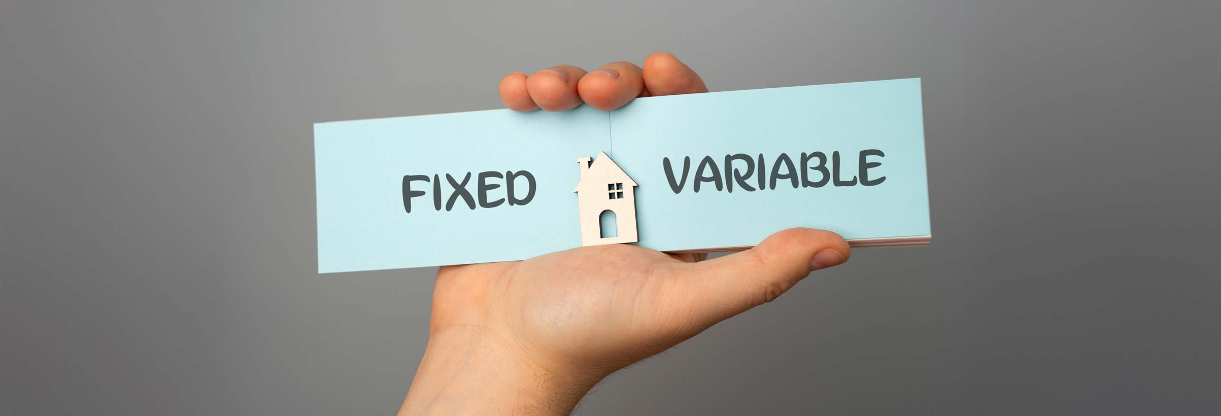 Mortgage rates concept. The inscription Fixed and Variable on a notebook in the hands of a man and a miniature house.