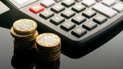 Piles of pound coins with calculator