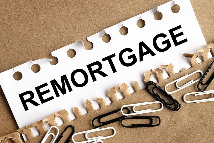 White sign with black writing which reads 'remortgage' and black and white paperclips underneath