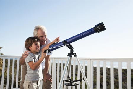A grandparent with their grandchild looking through a telescope