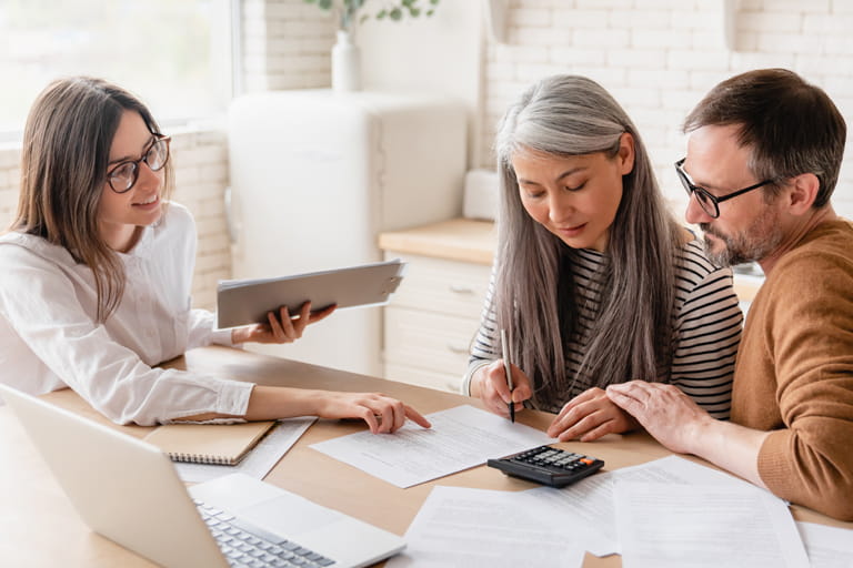 Three people sitting around a table looking at documents