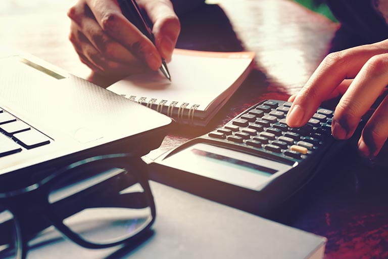 Close-up of a hands using a calculator and taking notes