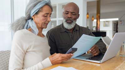 A couple looking through papers with a laptop and calculator to hand
