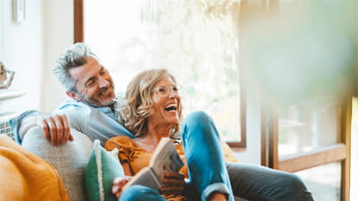 A man and woman sitting on a sofa laughing