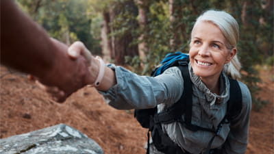 A woman hiking and taking an offered hand of support