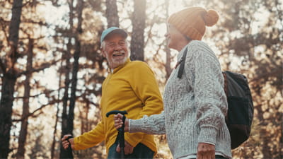A mature couple walking and smiling through woodland