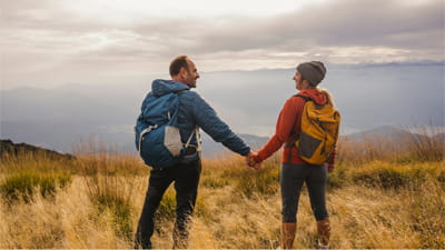 A couple holding hands while looking out on a view from the top of a hill