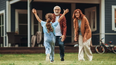 A young girl running towards her grandparents with her arms in the air
