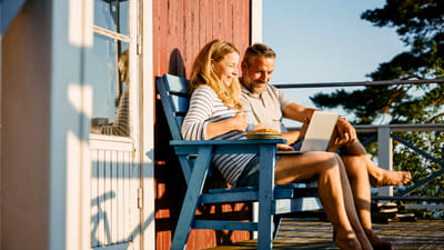 A couple sat in chairs on some decking in the sunshine