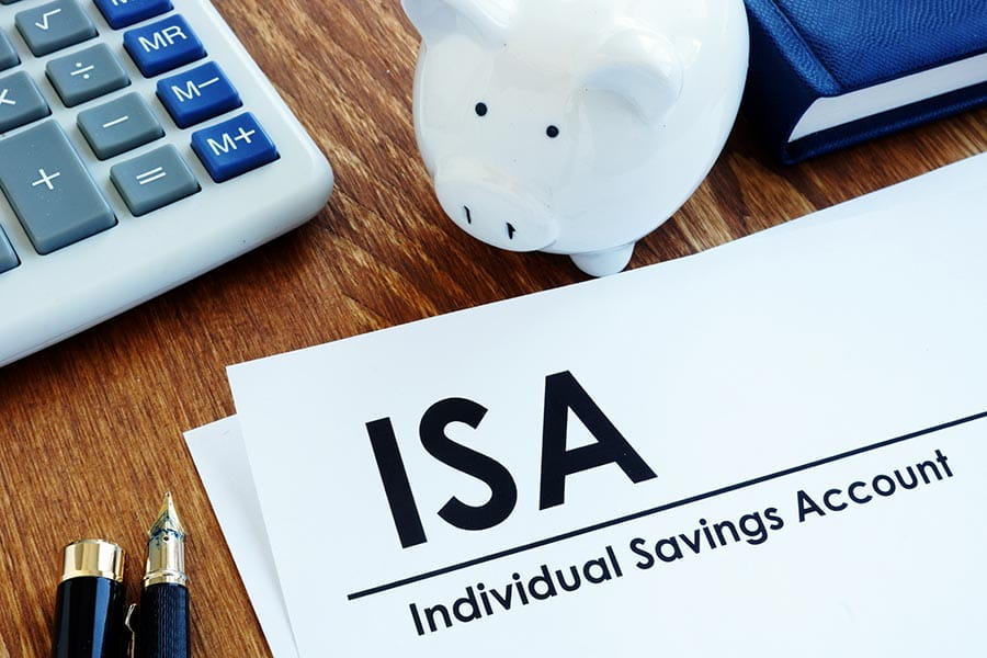 A desk with a computer, a piggy bank and some paperwork with the word Individual Savings Account printed at the top