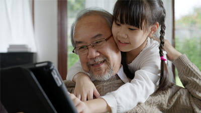 A grandfather looking at a book with his granddaughter