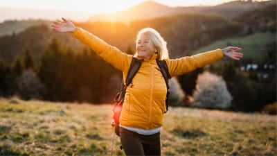 A woman with her arms open wide on a hillside