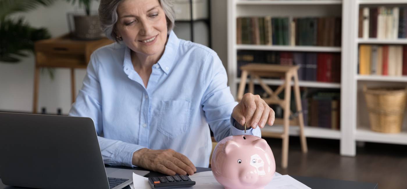 Happy middle-aged woman put coin into piggybank, save money for future, make investment. 
