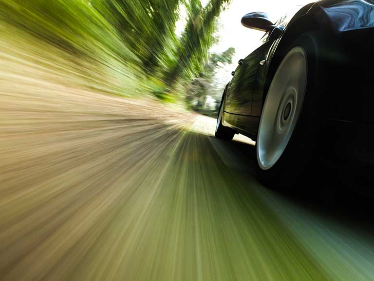 A car speeds along a country road, risking being hit by the speeding fine rise