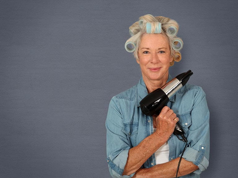 Mature lady thickening hair with rollers and hairdyer