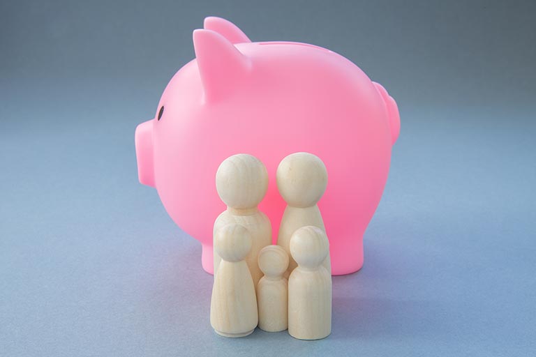 A piggy bank with models of a family in front of it